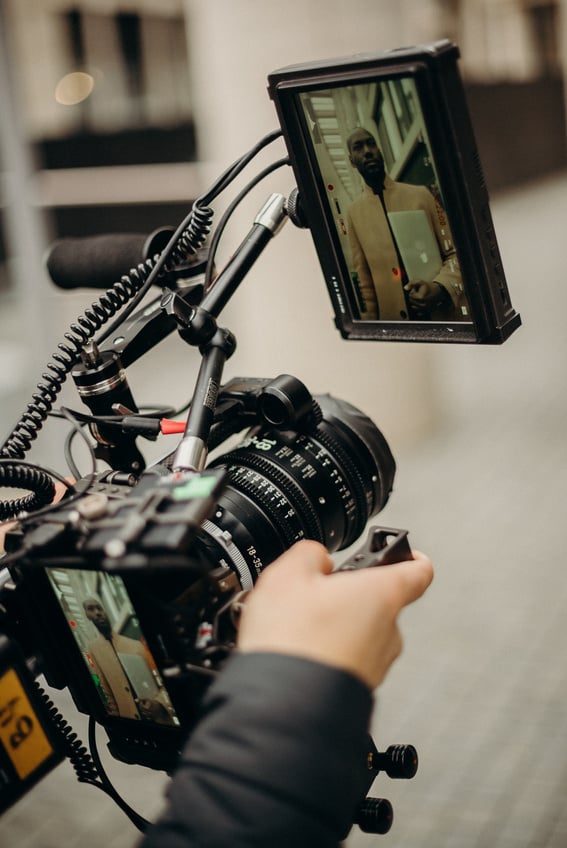 Person Holding Camera With Lens Facing Towards Man Wearing a Coat